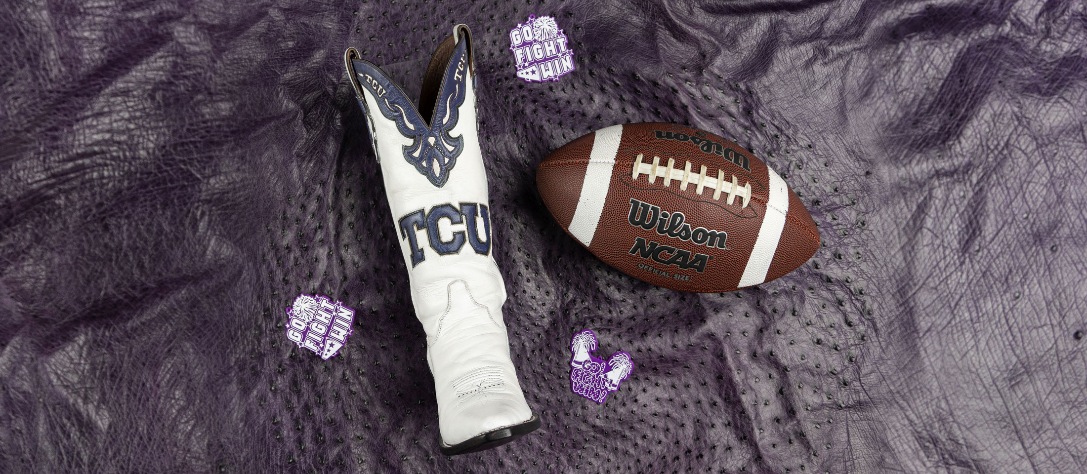 Custom boots made for TCU Showgirls next to a football on a purple background.